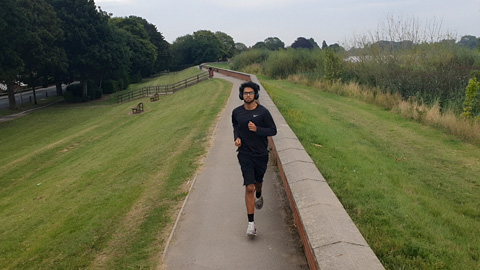 A person jogging on a paved path in a park.